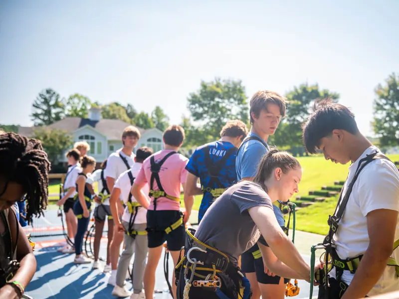 Guests getting fitted for climbing harnesses before safety training