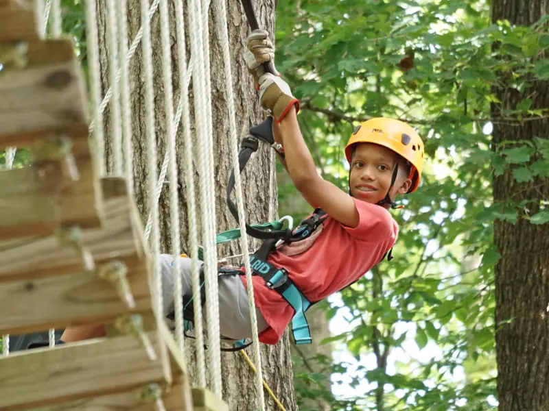 Kid smiling while climbing a cargo net at a birthday party