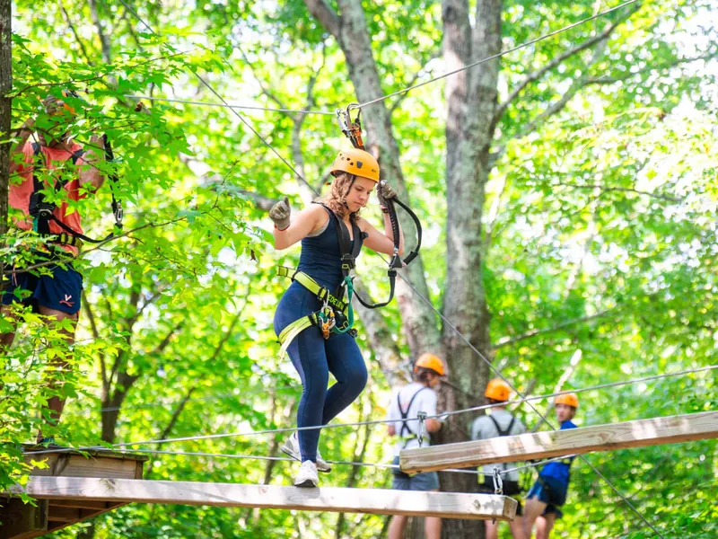 Group of friends cheering each other on from a ropes course platform